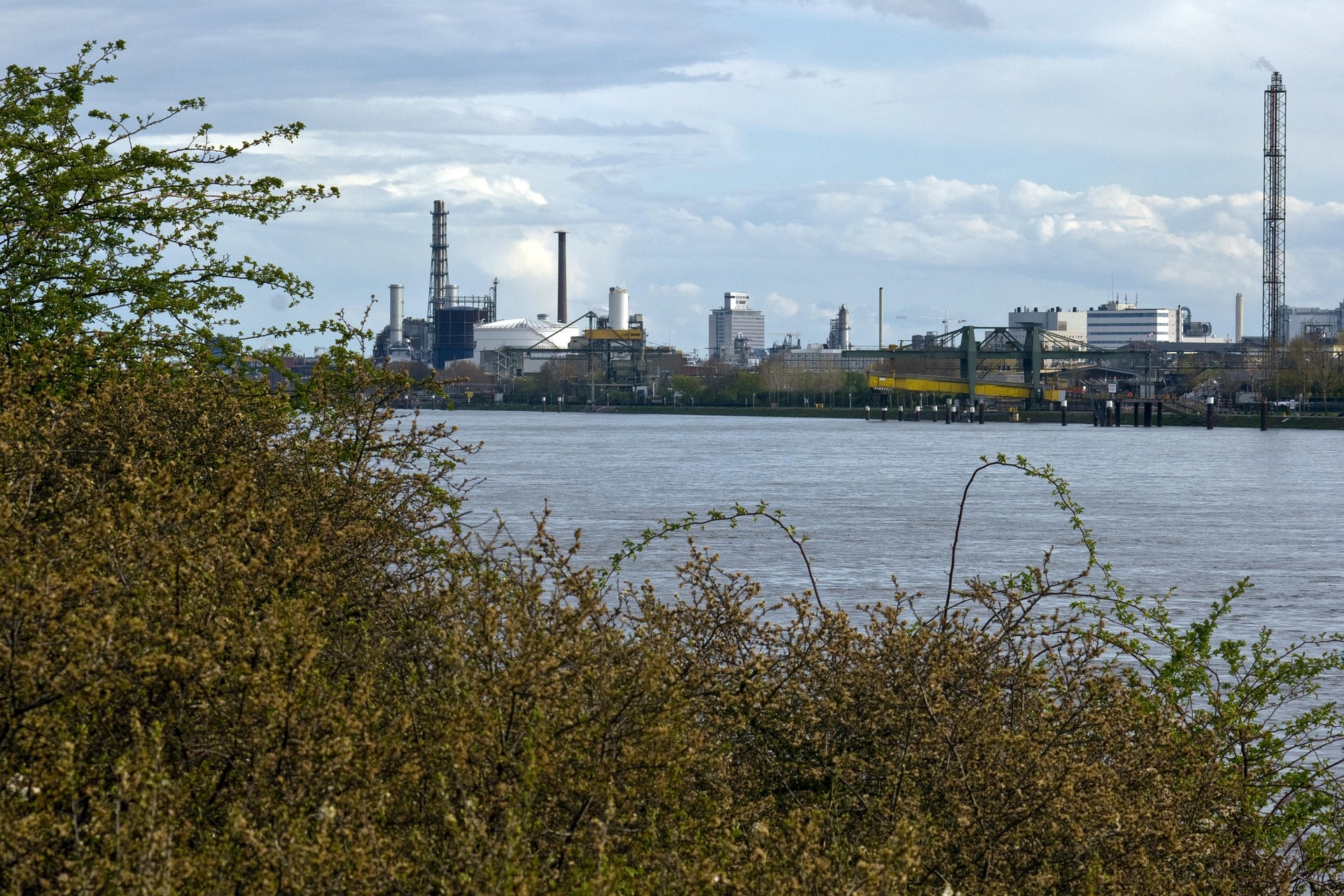 Das Foto zeigt den Rhein bei Ludwigshafen, im Hintergrund die Industriebauten von BASF.