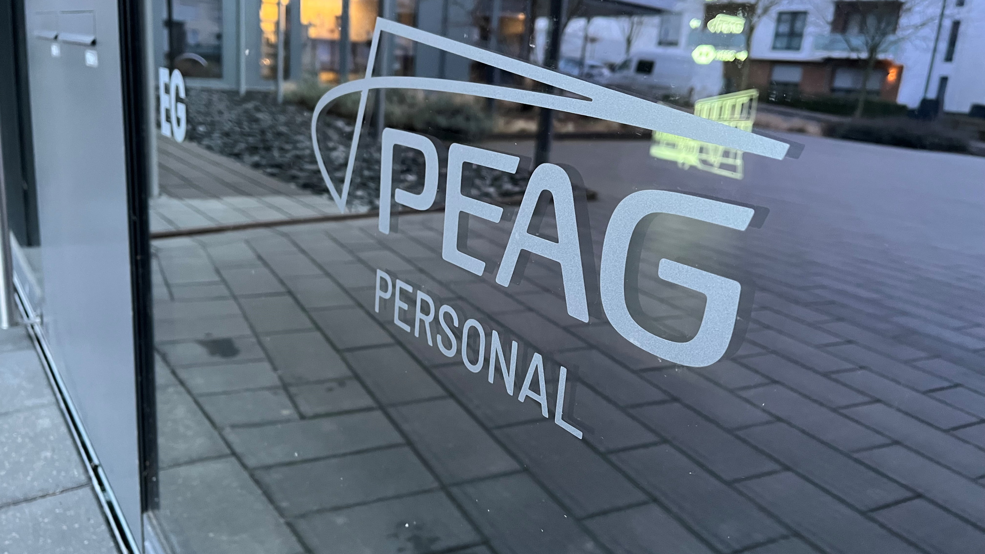 Das Bild zeigt den Eingang zur Niederlassung von PEAG Personal in Dortmund. Zu sehen ist das Logo auf einer Glasscheibe. 