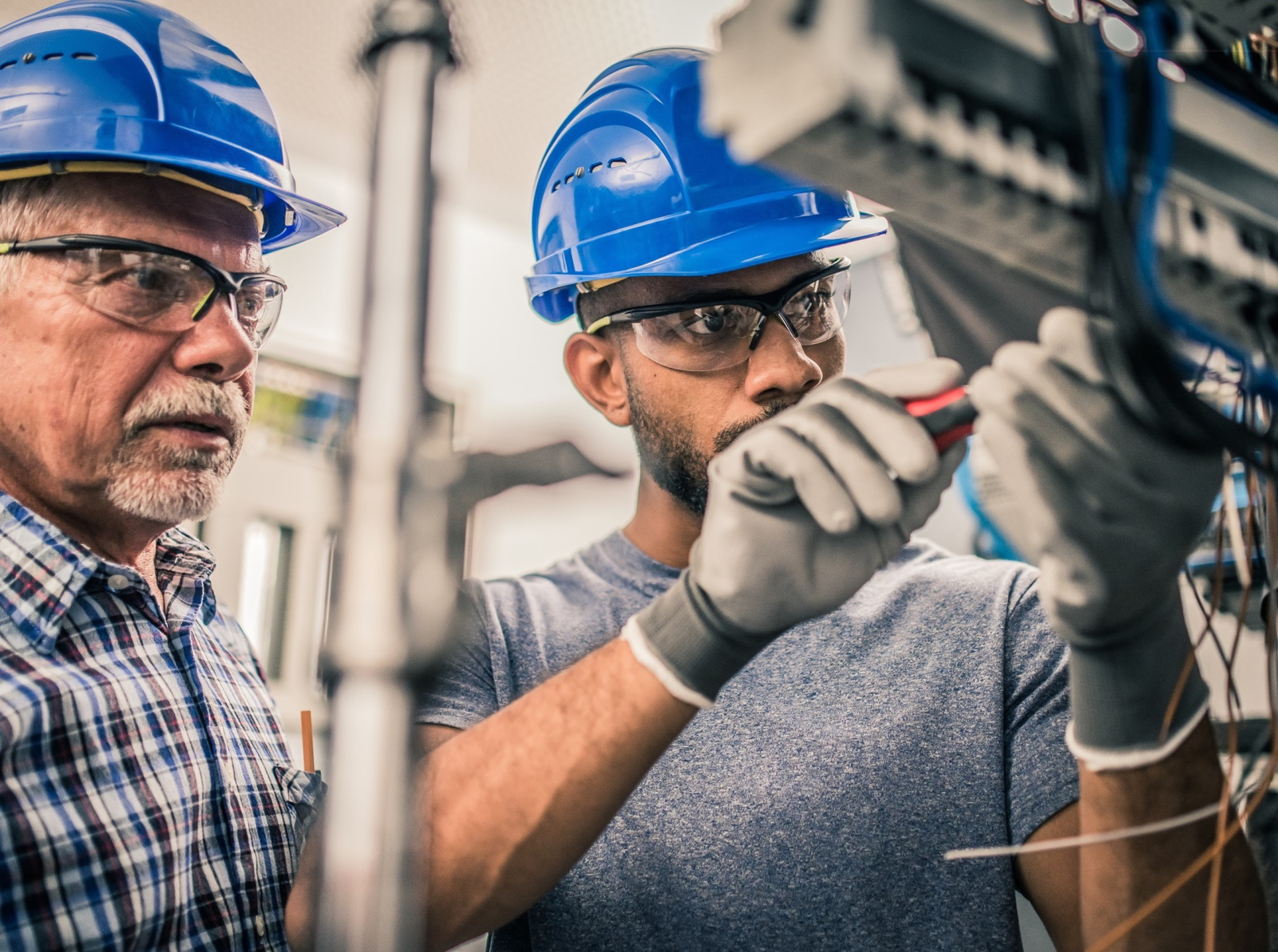 PEAG Personal überlässt Fachkräfte: Das Bild zeigt zwei Techniker mit Schutzhelm bei der Arbeit, älterer Vorgesetzter und sein Mitarbeiter.